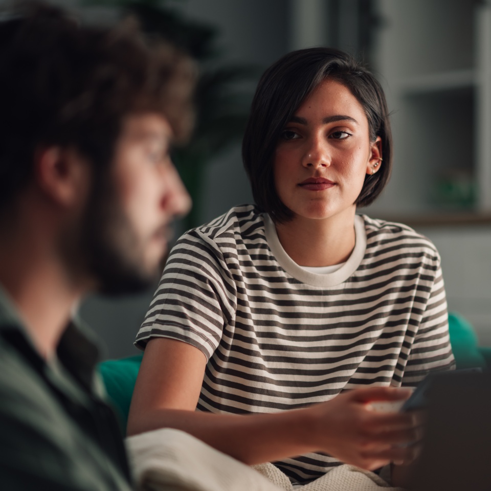 Young woman listening intently to her partner, sharing thoughts and having a serious discussion at home, focusing on relationship communication