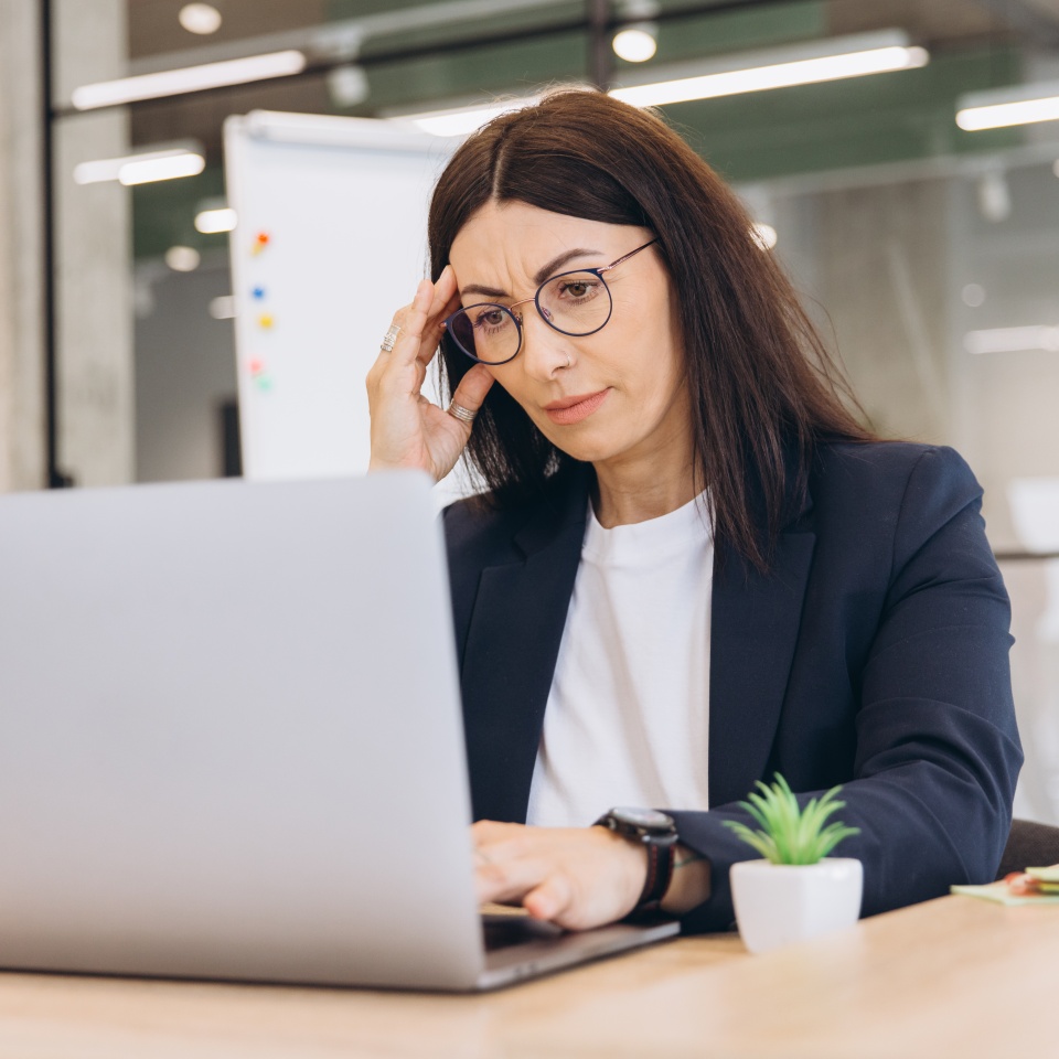Businesswoman experiencing headache from stressful work, feeling tired and overwhelmed at office desk, dealing with professional burnout
