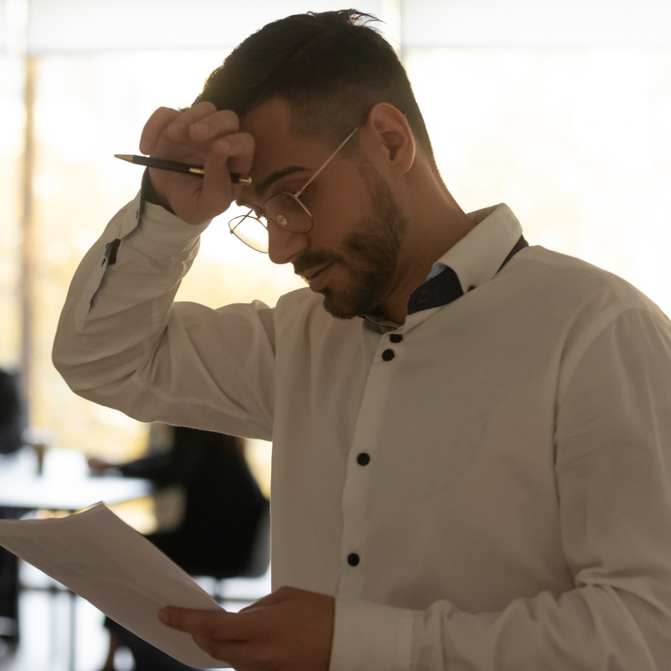 Stressed sweaty inexperienced businessman male speaker sweating wiping sweat holding paper reading preparing for speech, feeling nervous worried tedious waiting afraid of public speaking fear concept.