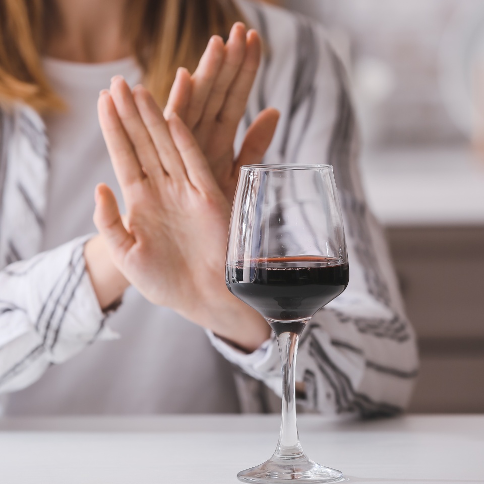 Woman refusing to drink wine at home. Concept of alcoholism