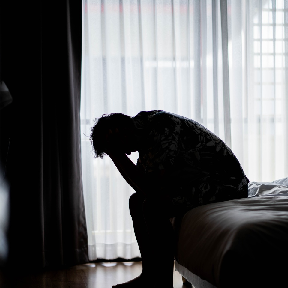 Lonely man silhouette feeling depressed and stressed sitting head in hands in the dark bedroom, Depression and anxiety disorder concept