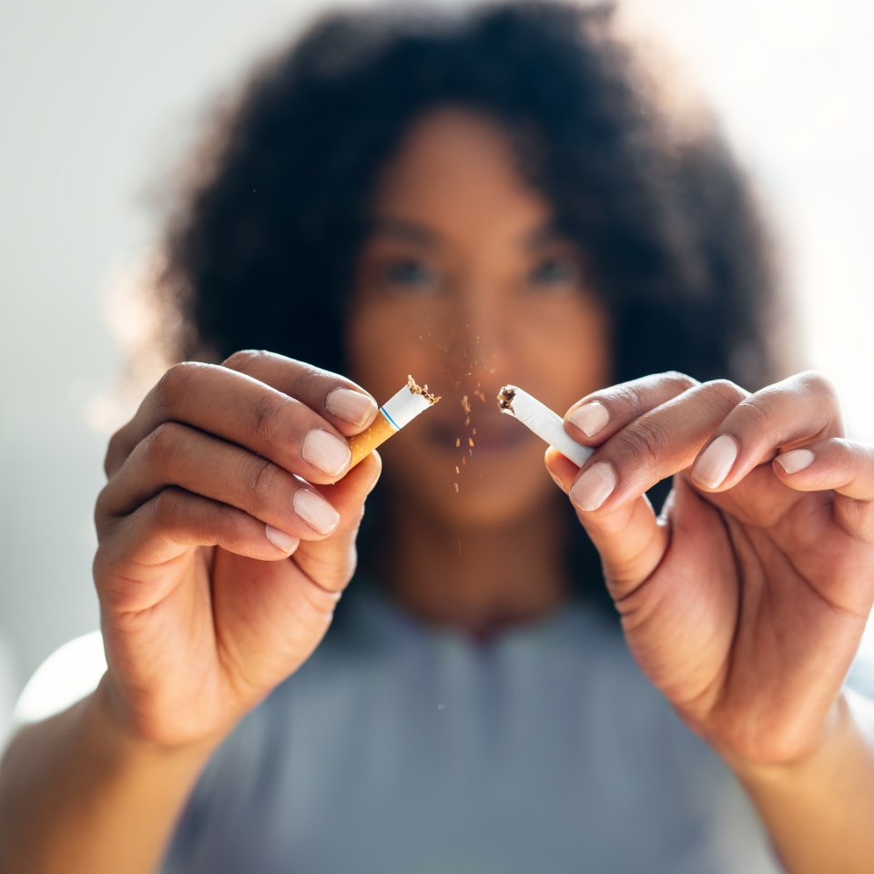 Close-up of woman breaking down cigarette to pieces. Quit smoking concept